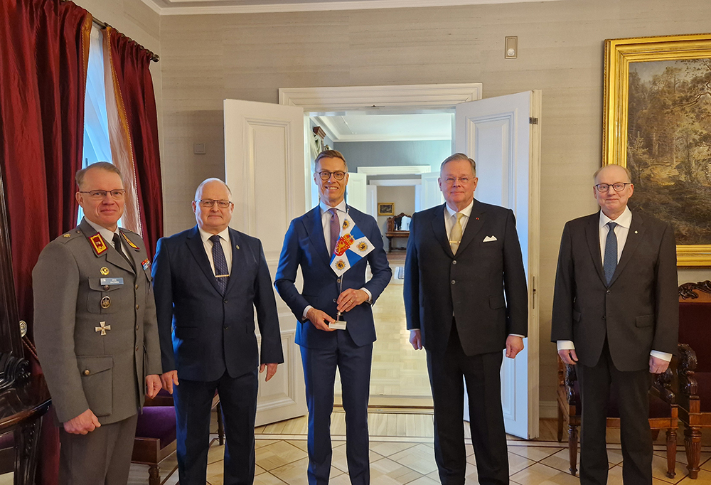 Henkilöt seisovat juhlavassa huoneessa.