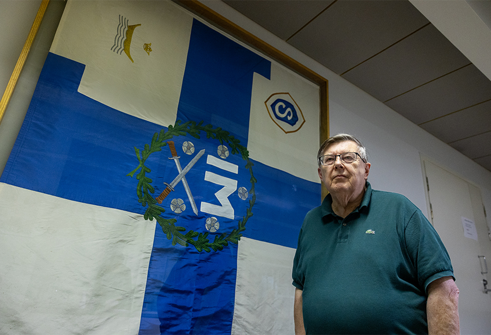 Helsingin Suojeluskuntapiirin Perinnekillan puheenjohtaja Markus Anaja ikämiessuojeluskunnan lipun edessä.