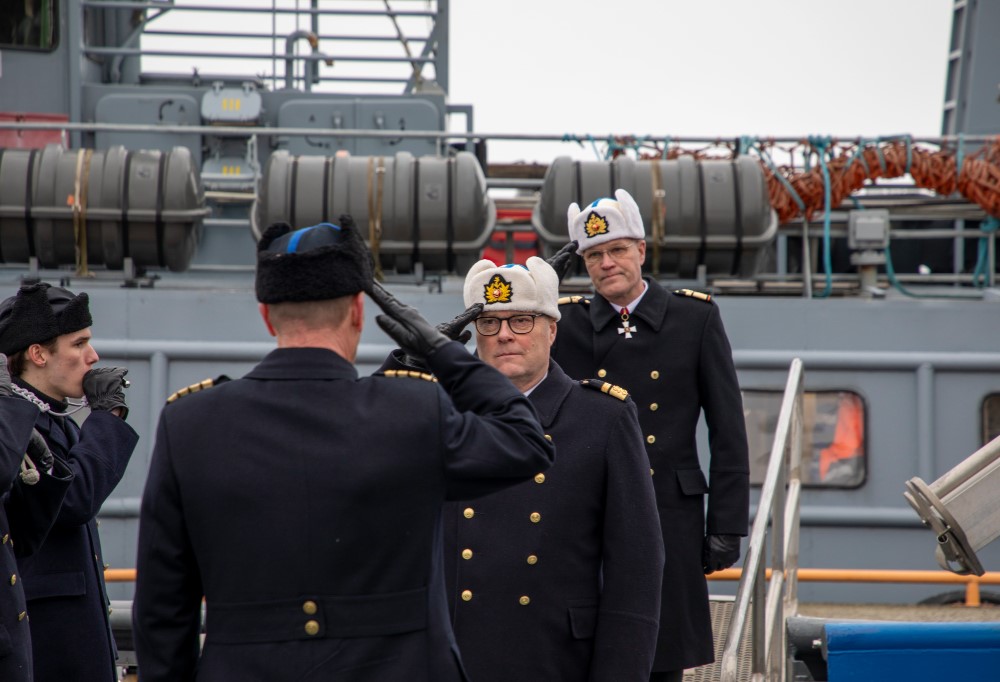 Amiraalit tervehtivät lipattaen jo aluksella olevaa Rajavartiolaitoksen kommodoria. Vasemmassa reunassa varusmies puhaltamassa pilliin.