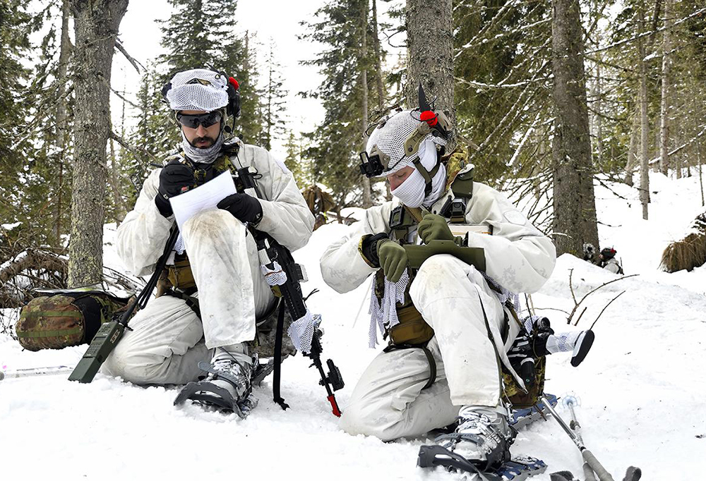 Kaksi italialaista sotilasta putsaavat aseita talvisissa oloissa.