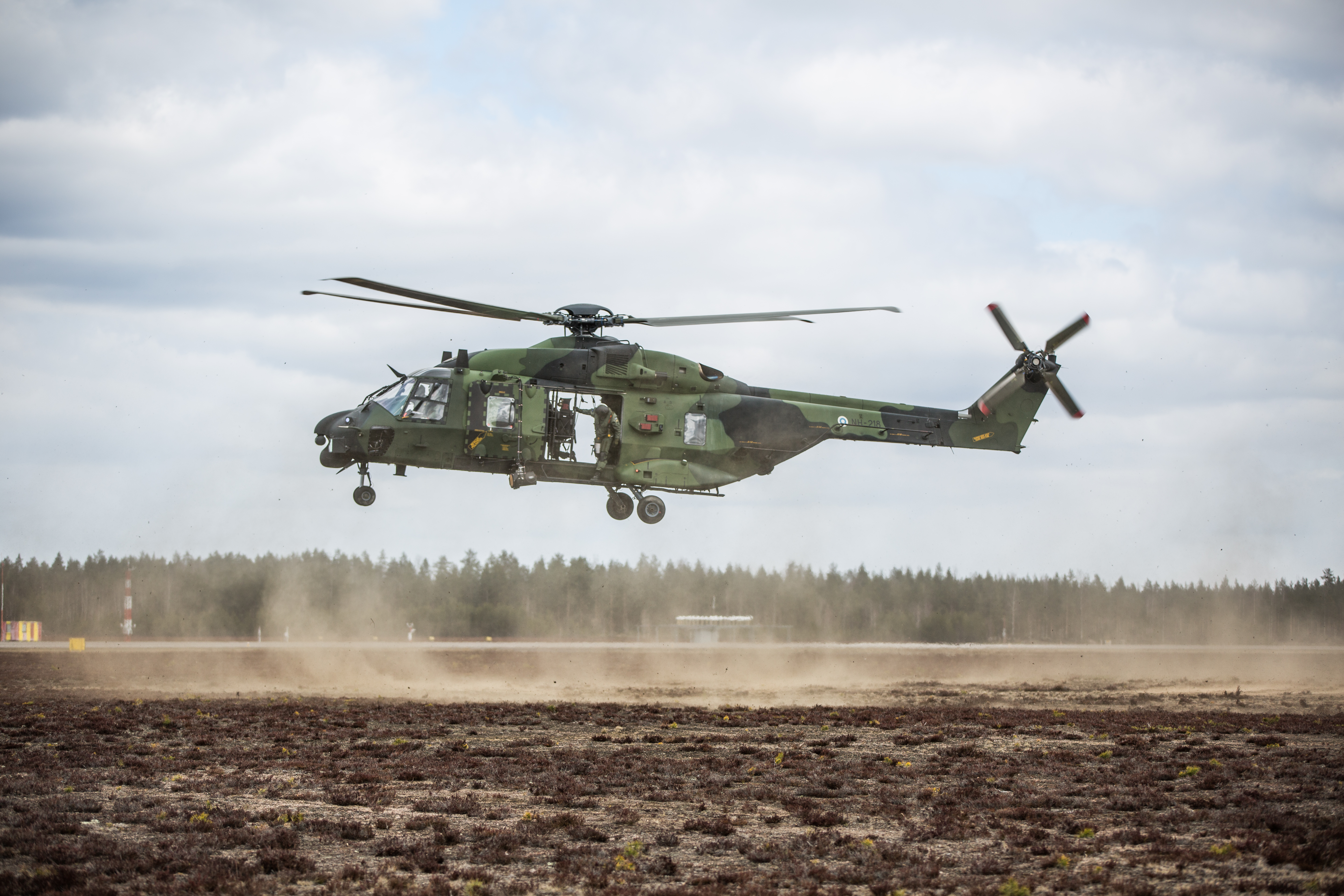 Kuljetushelikopteri lentämässä lähellä maanpintaa Utin lentokenttäalueella.
