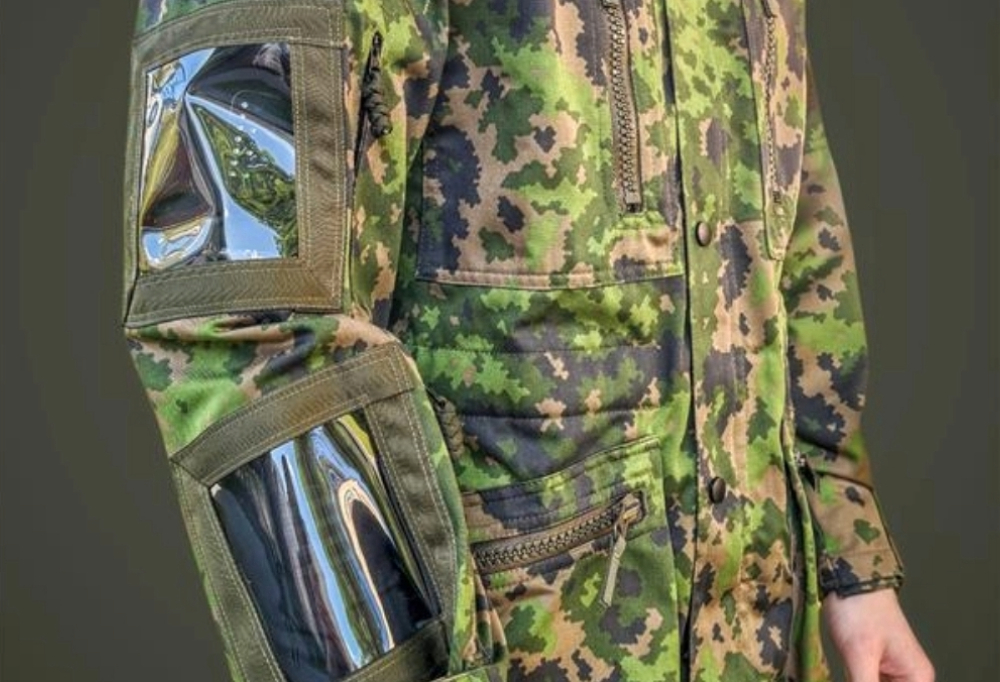 Kuvassa on maastopukuinen henkilö. jolla on kädessään älyhiha.