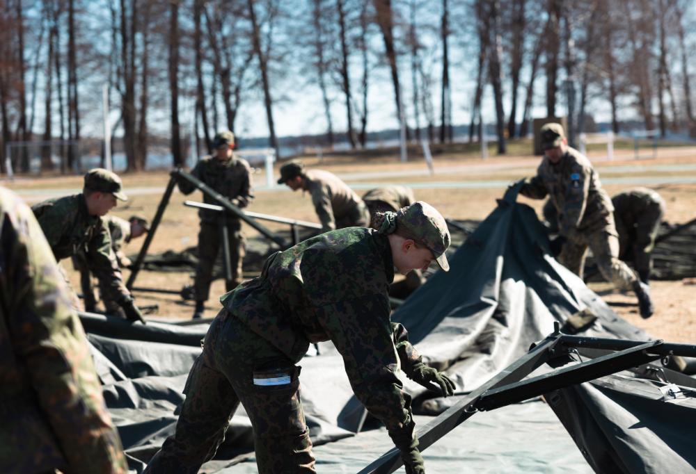 Varusmiehet työskentelevät suuren telttarakennelman parissa.