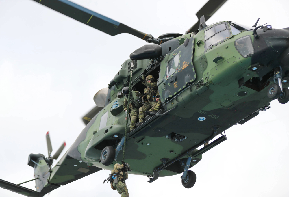 Kuvassa on NH-90 taisteluhelikopteri, josta sotilaat tiputtautuvat köyden varassa alas.