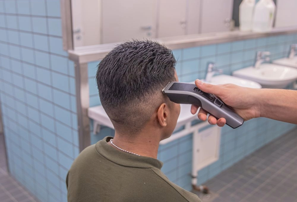 Kuvassa varusmiehen hiuksia ajellaan hiustenajokoneella lyhyemmiksi.