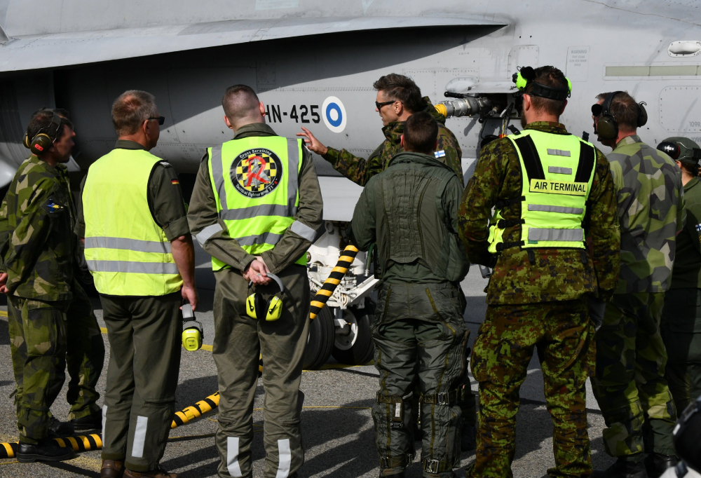 Ihmisiä puolikaaressa hävittäjän edessä.