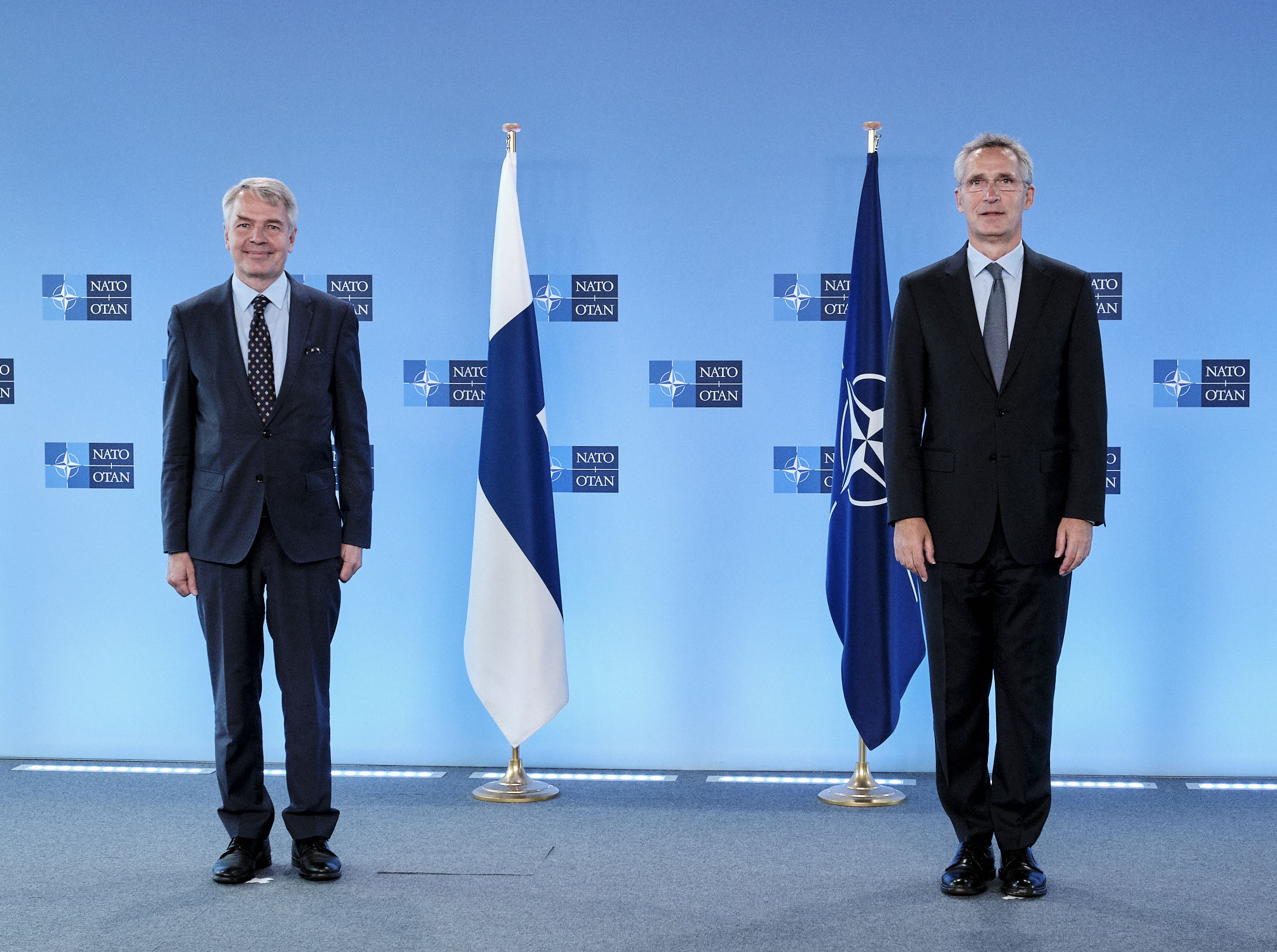 Pekka Haavisto ja Jens Stoltenberg seisomassa Suomen ja Naton lippujen edessä