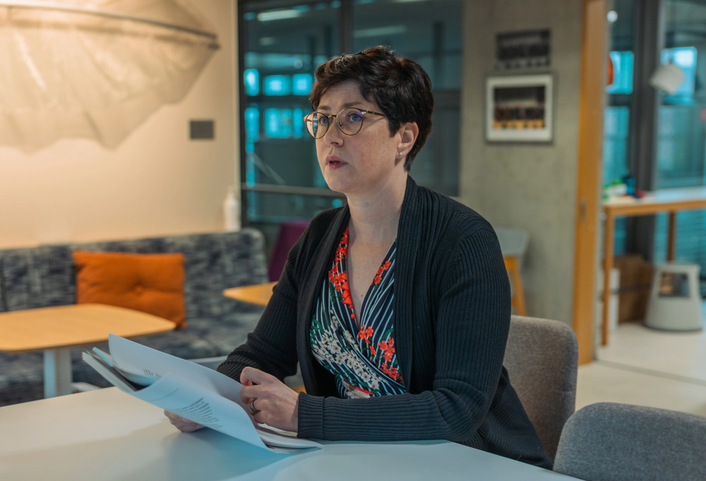 Kuvassa erikoissyyttäjä Krista Mannerhovi istuu tuolilla paperinippu kädessä.