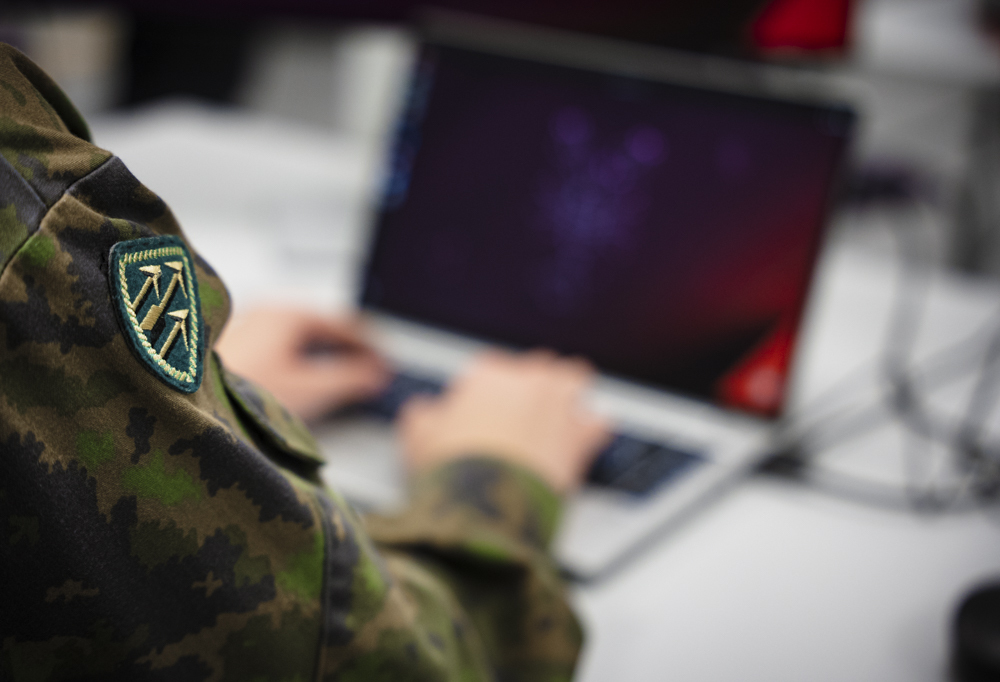 Kybervarusmies suorittamassa palvelustehtäväänsä kannettavan tietokoneen ääressä.