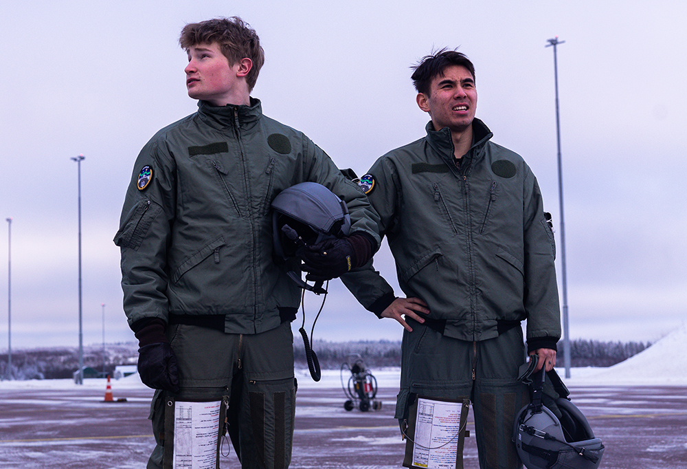 Kuvassa upseerioppilaat seisovat lentovarusteissa kiitoradan läheisyydessä.