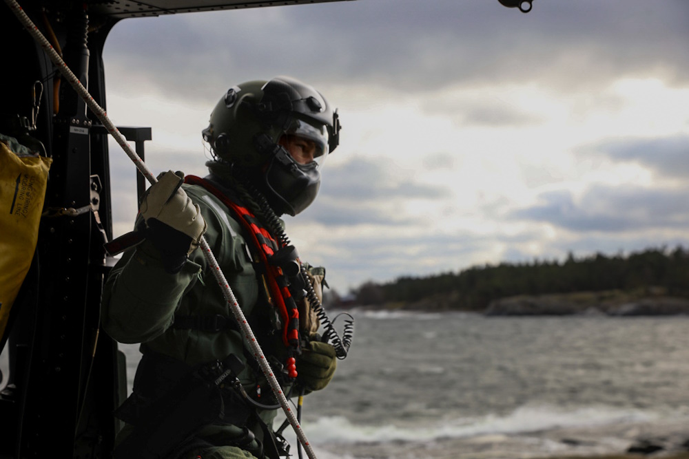 Kuvassa helikopterin miehistönjäsen katsoo helikopterin sivuovesta ulos.