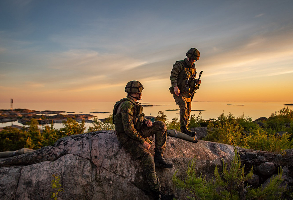 Kaksi suomalaista sotilasta katselee auringonlaskua.