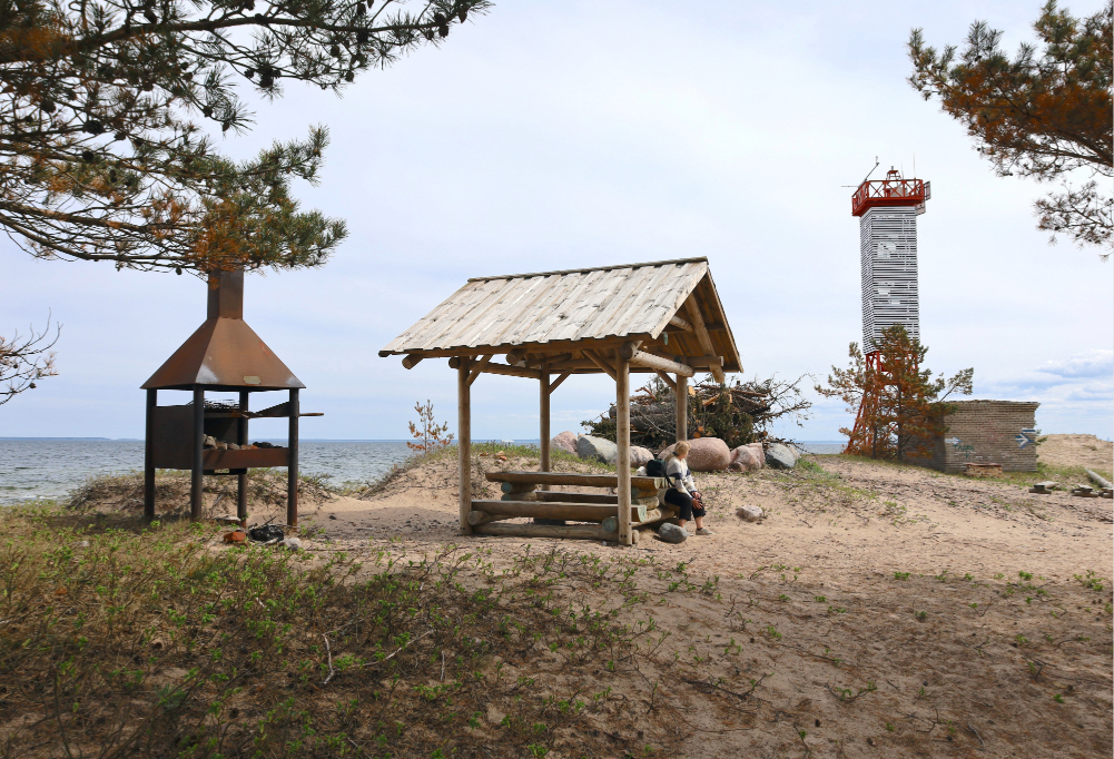 kuvassa näkyy rantamaisema, jossa lepäilee retkeilijä