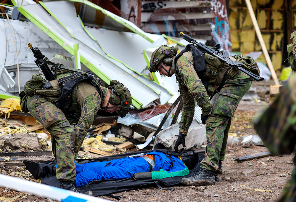 Kuvassa sotilaat kantavat harjoitusnukkea pois onnettomuuspaikalta.