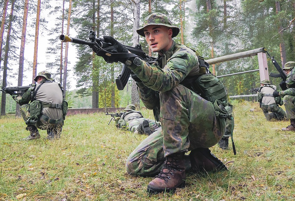 Varusmies aseen kanssa ulkona.