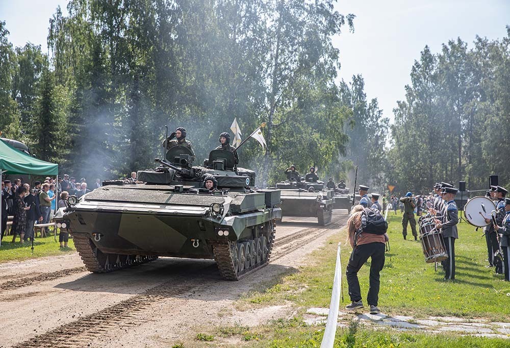 Kuvassa panssariajoneuvoja ja sotilassoittokunta.