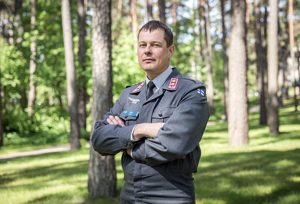 Everstiluutnantti Simo Pesu seisoo uniformussa luonnossa kädet puuskassa