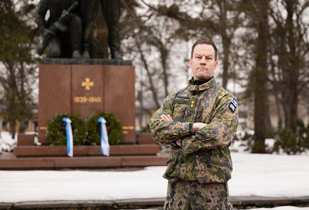 Kuvassa everstiluutnantti Tino Savolainen katsoo kädet puuskassa vakavasti kameraan.