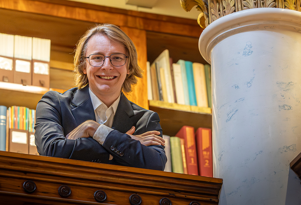 Kuvassa Casper Enckell nojaa puiseen kaiteeseen ja katsoo kameraan hymyillen.