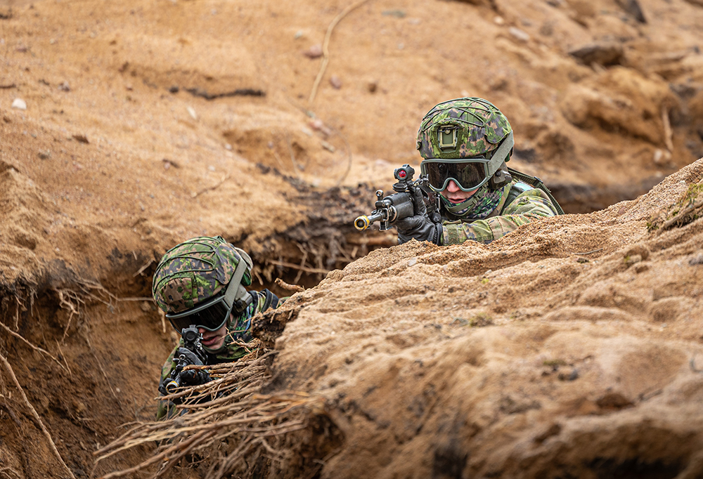 Kuvassa kaksi varusmiestä tähtäävät aseilla tuliasemasta.