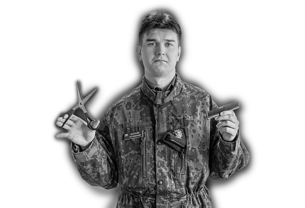 Kaartinjääkäri Lähteenmäki katsoo kameraan surullisena kädessään sakset ja kampa.