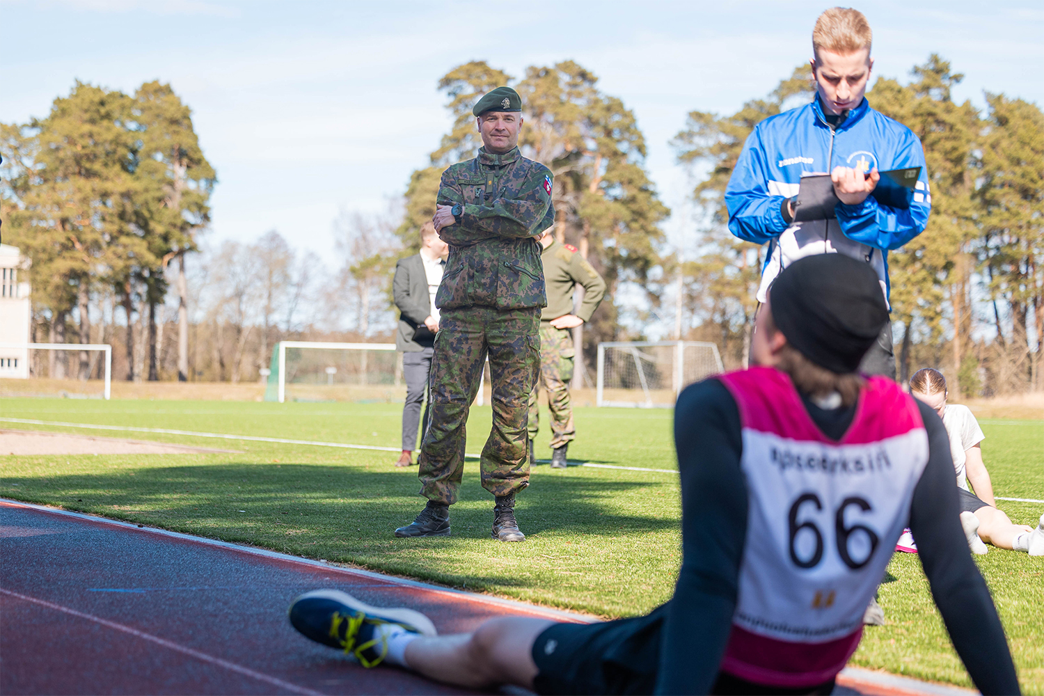 Kuvassa Maanpuolustuskorkeakoulun rehtori, prikaatikenraali Jaro Kesänen katsoo Cooperin testin juossutta hakijaa, joka istuu maassa.