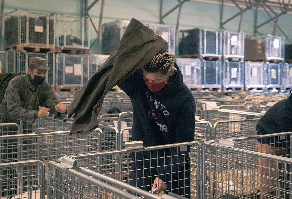 Kotiutuva varusmies laittamassa varusteitaan rullakkoon varustevarastolla.