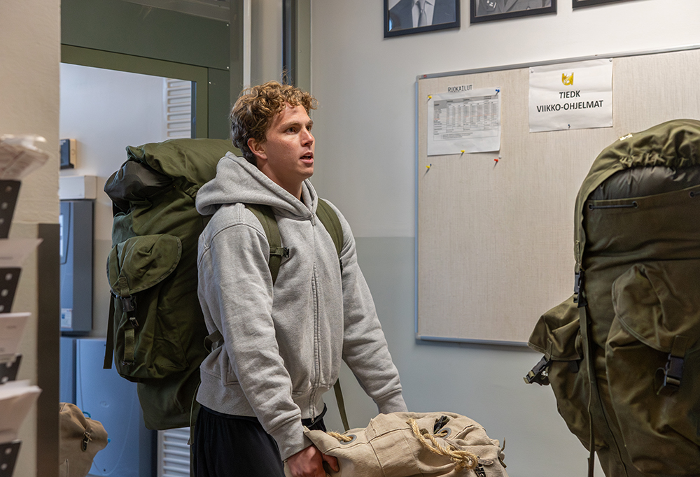 Jalkapalloilija kantamassa varusteitaan komppanian ovesta sisään.