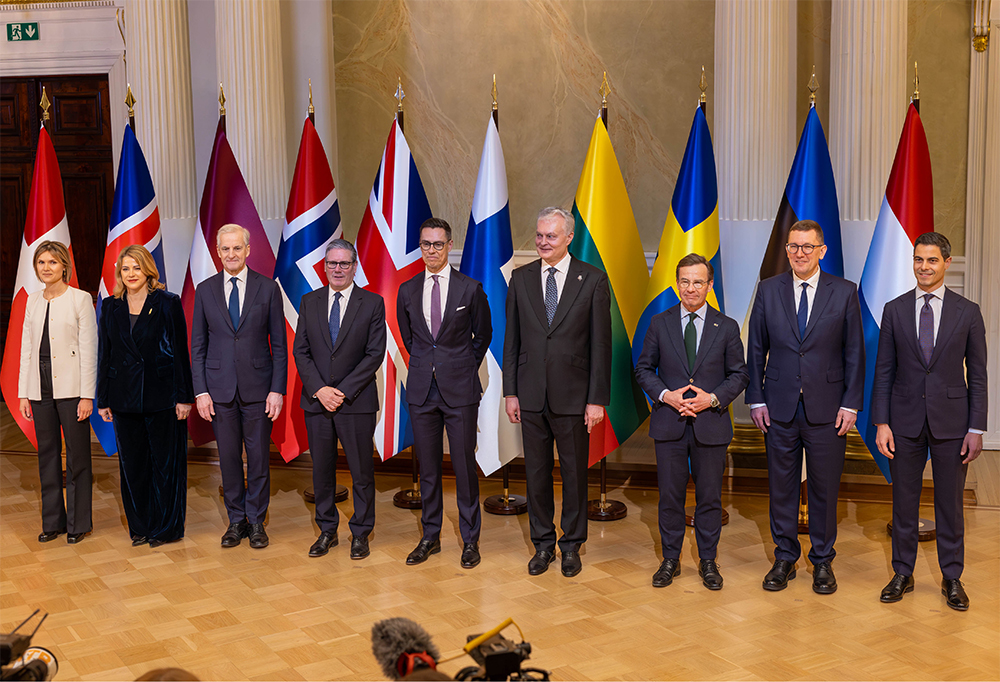 Kuvassa Jef-maiden johtajat seisovat rivissä maidensa lippujen edessä. Keskellä seisoo tasavallan presidentti Alexander Stubb.