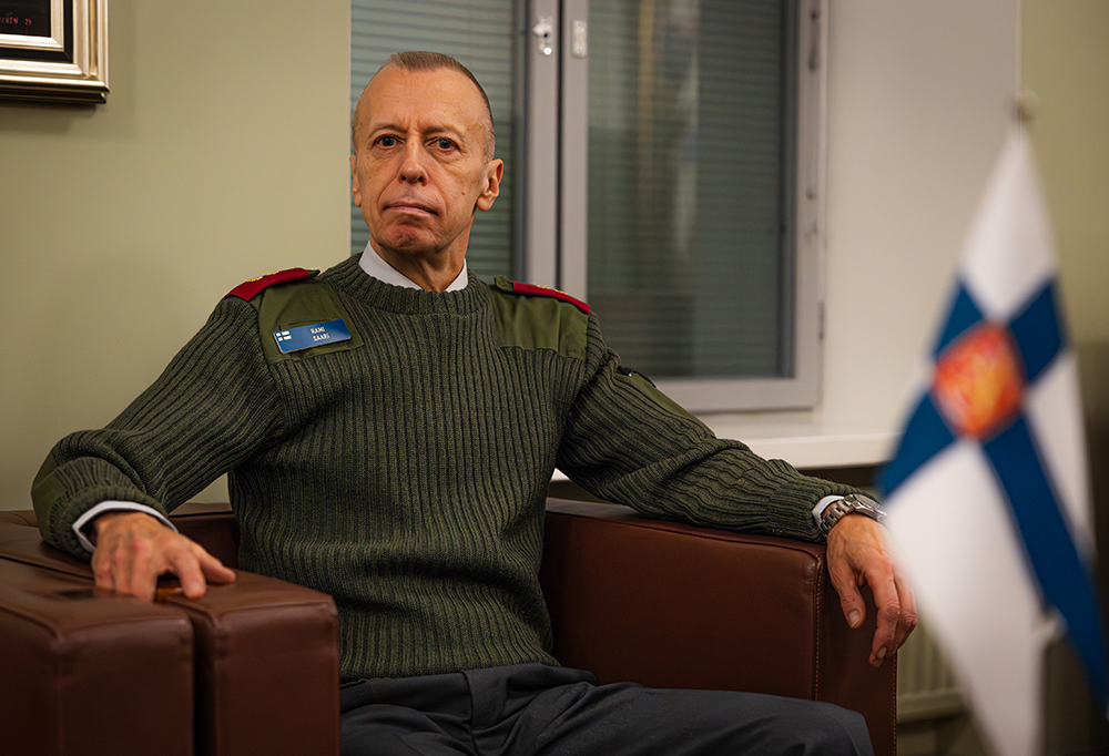 Kenraaliluutnantti Rami Saari katsoo kameraan ja istuu tuolilla.