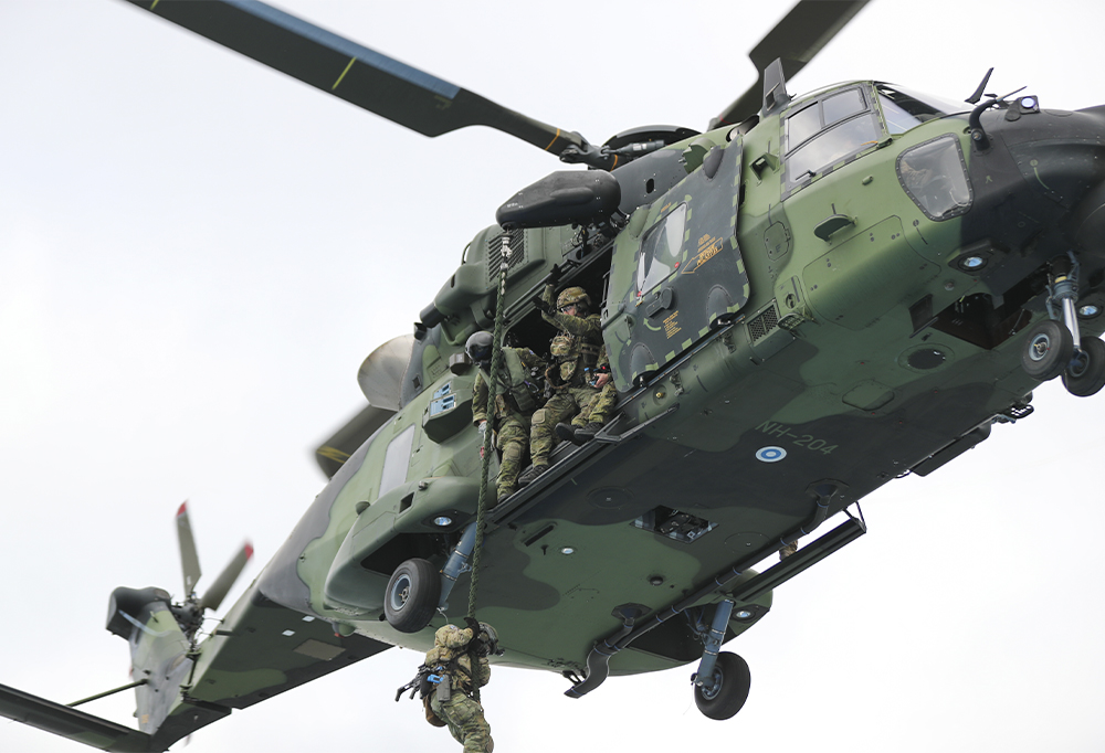 Taistelija laskeutuu köyttä pitkin lentävästä NH-90-kuljetushelikopterista.