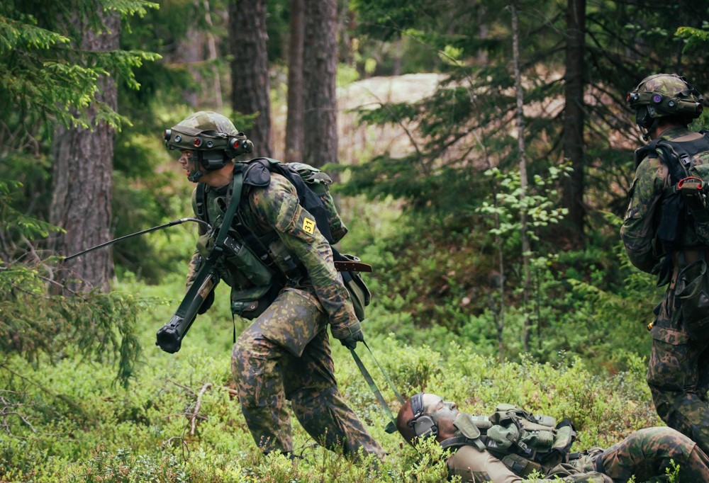 Kuvassa varusmiehet suorittavat haavoittuneen taistelijan evakuointia,