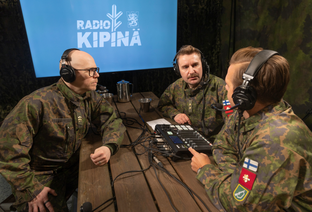 Joonas Nordman, Ilkka Ihamäki ja Toni Wirtanen äänittävät Radio Kipinä -podcastia maastopuvut päällään.