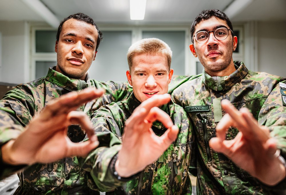 Kuvassa vasemmalta oikealle kaartinjääkäri Jeremy Seppänen, upseerikokelas Vilhelm Vähäsilta sekä kaartinjääkäri Saman Masoud näyttämässä sormillaan numeroa nolla jäljellä olevia aamuja kuvastaakseen.