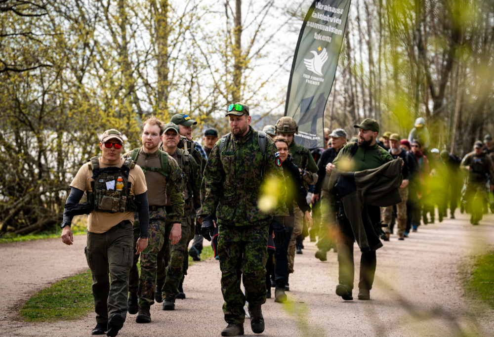 Kuvassa marssii joukko ihmisiä maastovaatetuksessa.