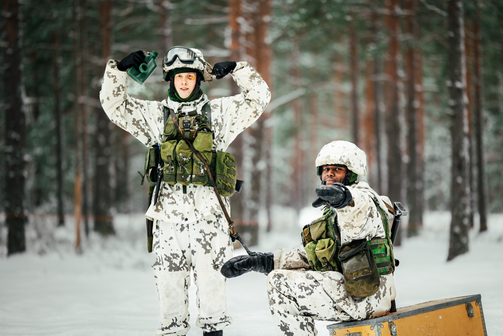 Kuvassa kaksivarusmiestä maastoutuvat lumiseen metsämaisemaan