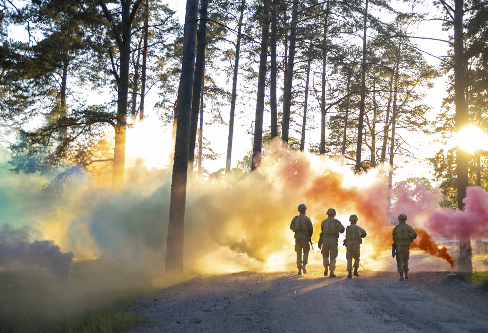 Kuvassa neljä sotilasta ja savukranaattien muodostama sateenkaarenvärinen pilvi.